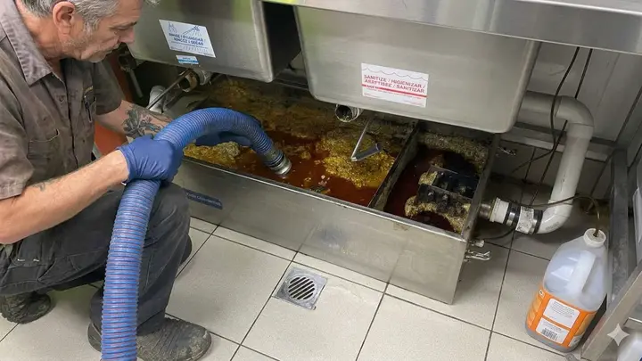 Technician servicing an outdoor grease interceptor at a Bend, Oregon restaurant